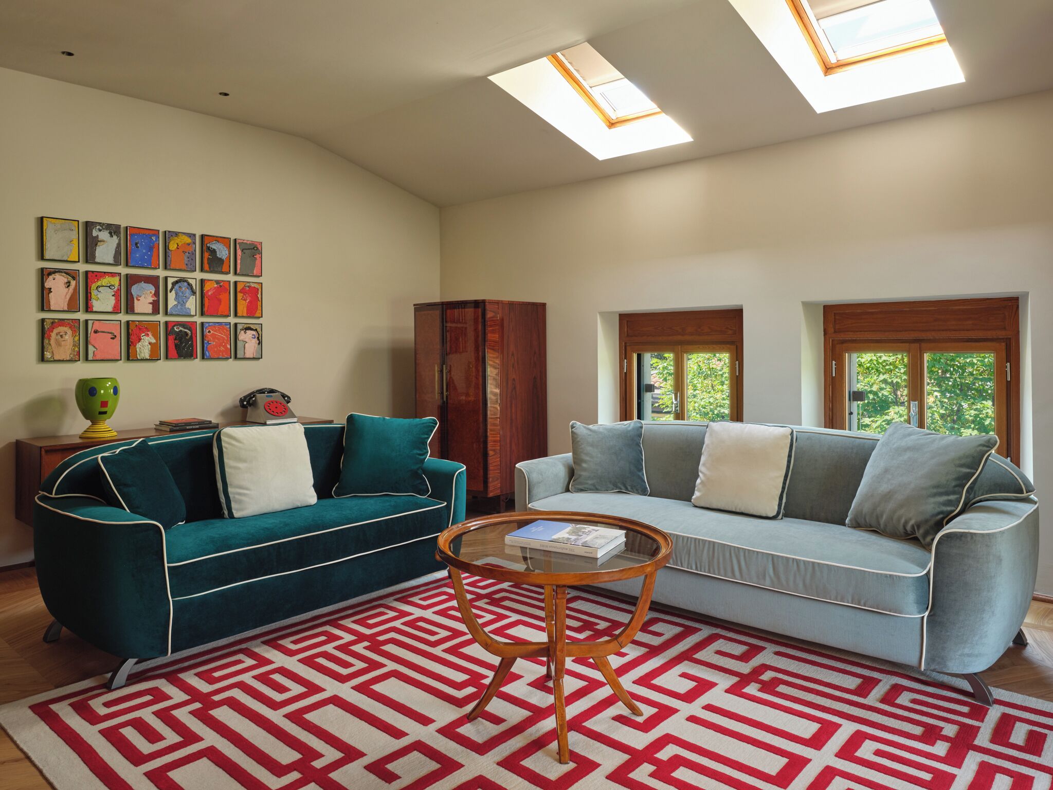 Ein Wohnzimmer mit zwei Sofas, einem Couchtisch, einem gemusterten Teppich und Kunstwerken an der Wand.