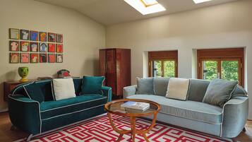 Ein Wohnzimmer mit zwei Sofas, einem Couchtisch, einem gemusterten Teppich und Kunstwerken an der Wand.