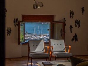 A room with two chairs facing a window overlooking a marina with boats.