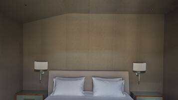 A hotel room with a large bed, two bedside tables, and wall-mounted lamps.
