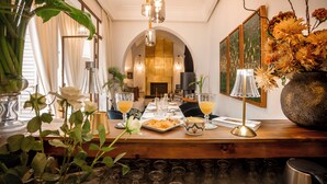 A dining area with a long table, chairs, a vase of flowers, and a chandelier. - Riad Anaqa (Marrakech)