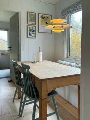 A dining area with a wooden table, chairs, a candle, and wall art.