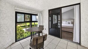 Una habitación con una mesa de comedor y sillas, una cama con vistas y una puerta corrediza de vidrio a un espacio al aire libre.