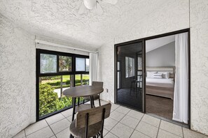 Ein Zimmer mit Esstisch und Stühlen, einem Bett mit Blick und einer Schiebeglastür zu einem Außenbereich.