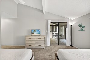 Ein Schlafzimmer mit zwei Betten, einem Schminktisch, einem Gemälde und Blick auf einen Balkon.