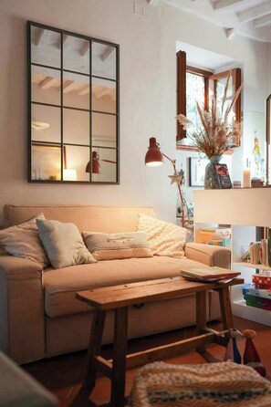 Ein gemütliches Wohnzimmer mit einer Couch, einem Couchtisch, einer Lampe und einem Bücherregal.