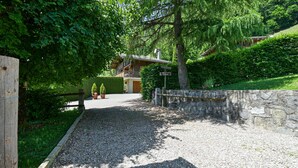 A gravel driveway leading to a wooden building with a stone wall and a signpost. - La Télécabine Guest Room (La Balme-de-Thuy)