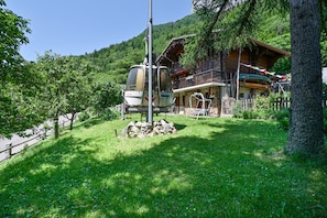 A mountain lodge with a cable car, surrounded by lush greenery and a wooden building with a balcony.