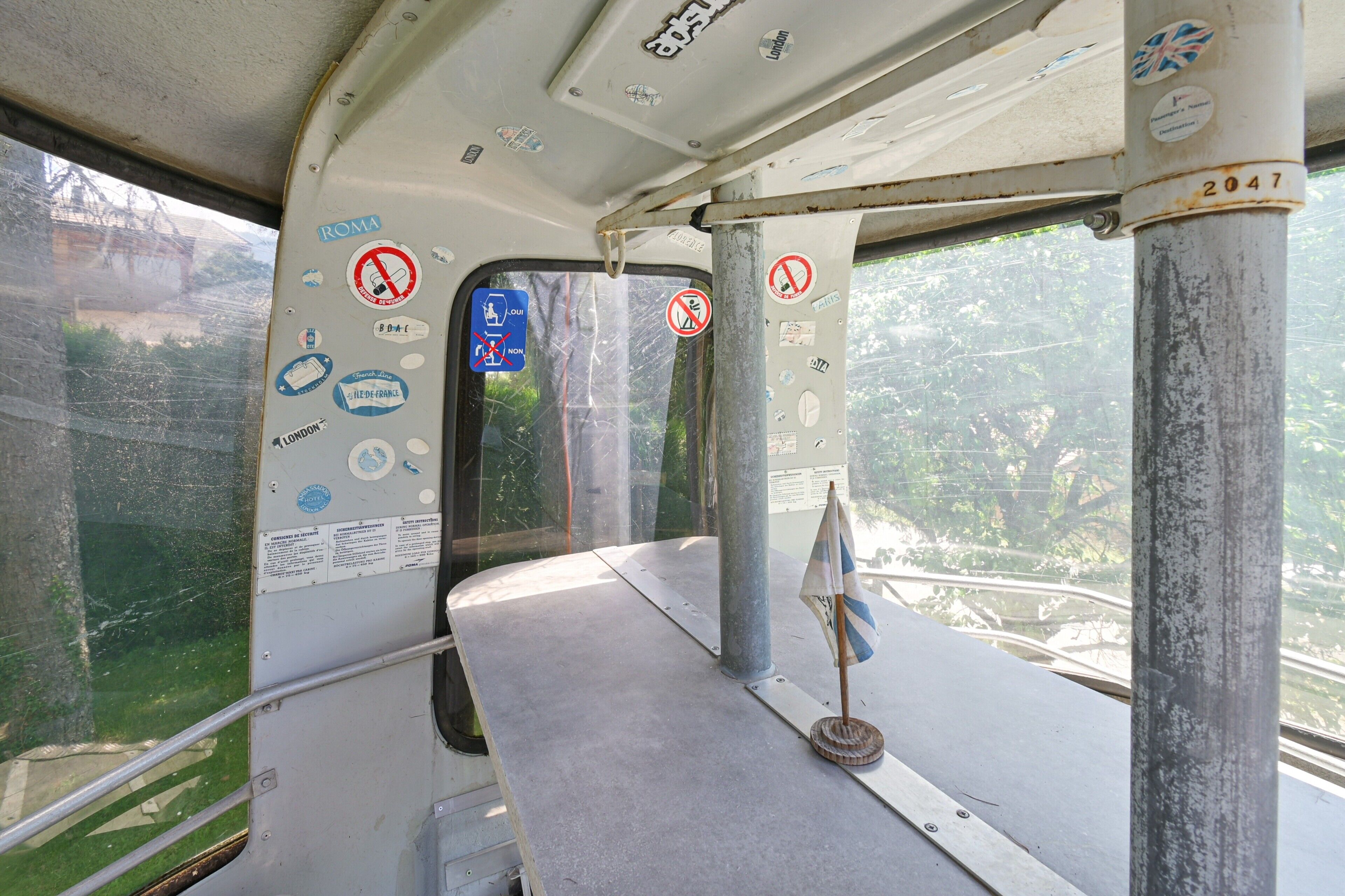 L'intérieur d'un autobus, avec un banc en métal, une fenêtre et divers autocollants sur les parois.