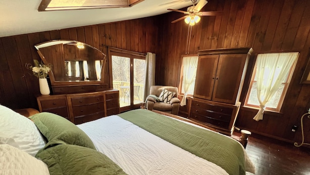 Una camera da letto con un letto grande, mobili in legno, una ventola a soffitto e una vista dalla finestra.