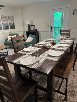 A dining room with a long wooden table set for six, surrounded by dark wooden chairs. - Serene 3-bedroom creekside cabin close to Blue Ridge (Morganton)