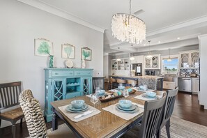 A dining area with a wooden table set for four, a blue cabinet, and a chandelier.