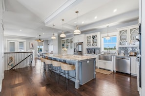 A spacious kitchen with a large island, pendant lighting, and white cabinetry.