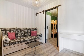 A room with a patterned sofa, a small table, a sliding door, and a wooden ladder.
