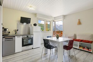 A modern kitchen with a built-in oven, a dishwasher, and a TV mounted above the stove.
