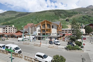 A hotel with a balcony, a pharmacy, and a view of a green hillside.