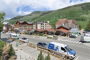 A hotel with multiple floors, a parking area, and a view of a mountainous landscape.