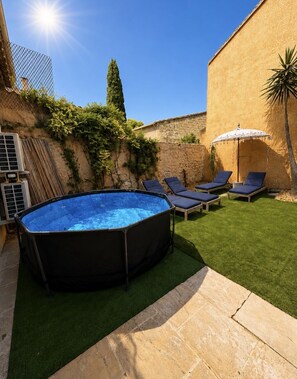 An outdoor swimming pool with lounge chairs and a palm tree.