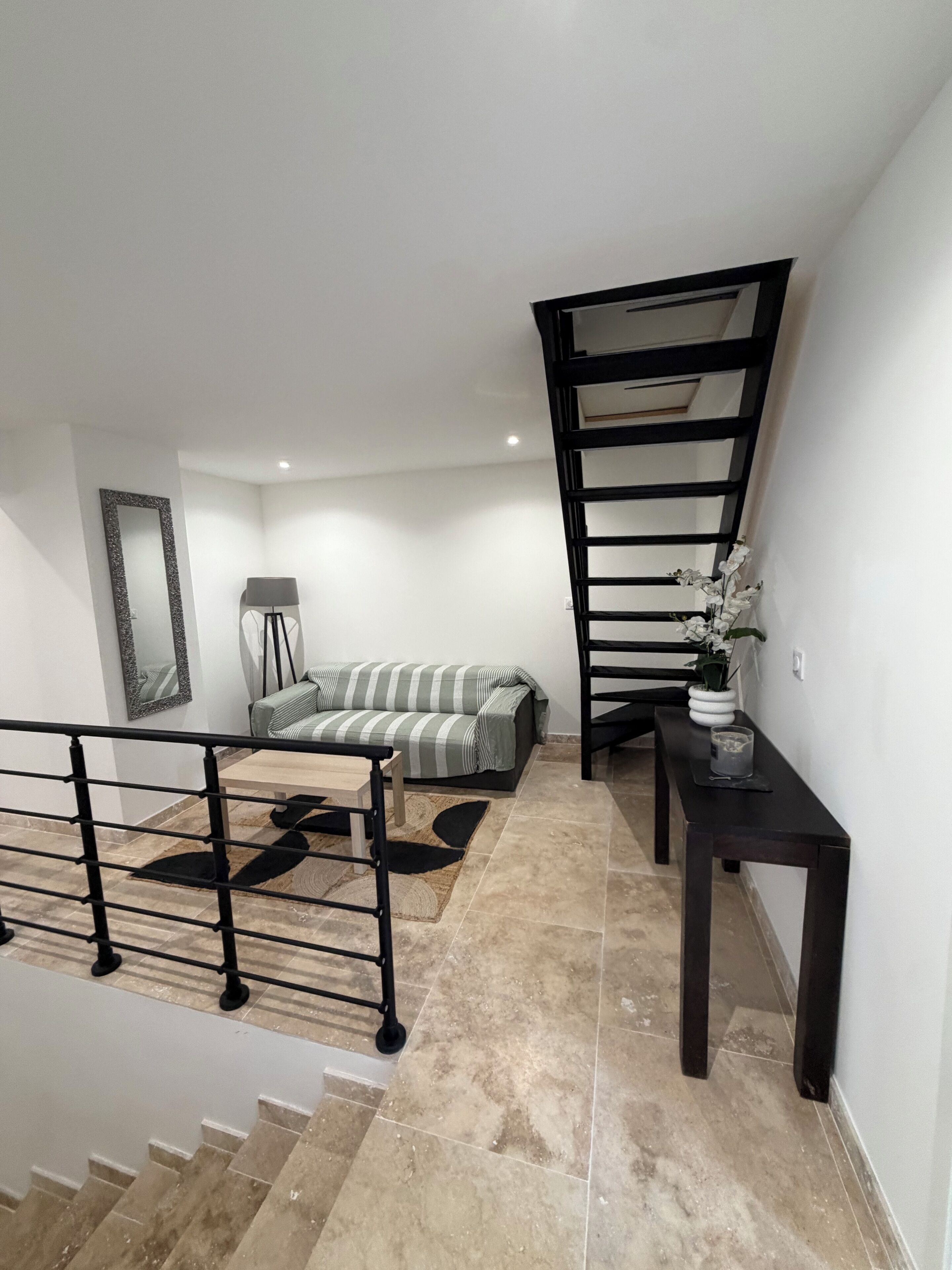 A modern interior with a staircase, a sofa, a lamp, and a small table.