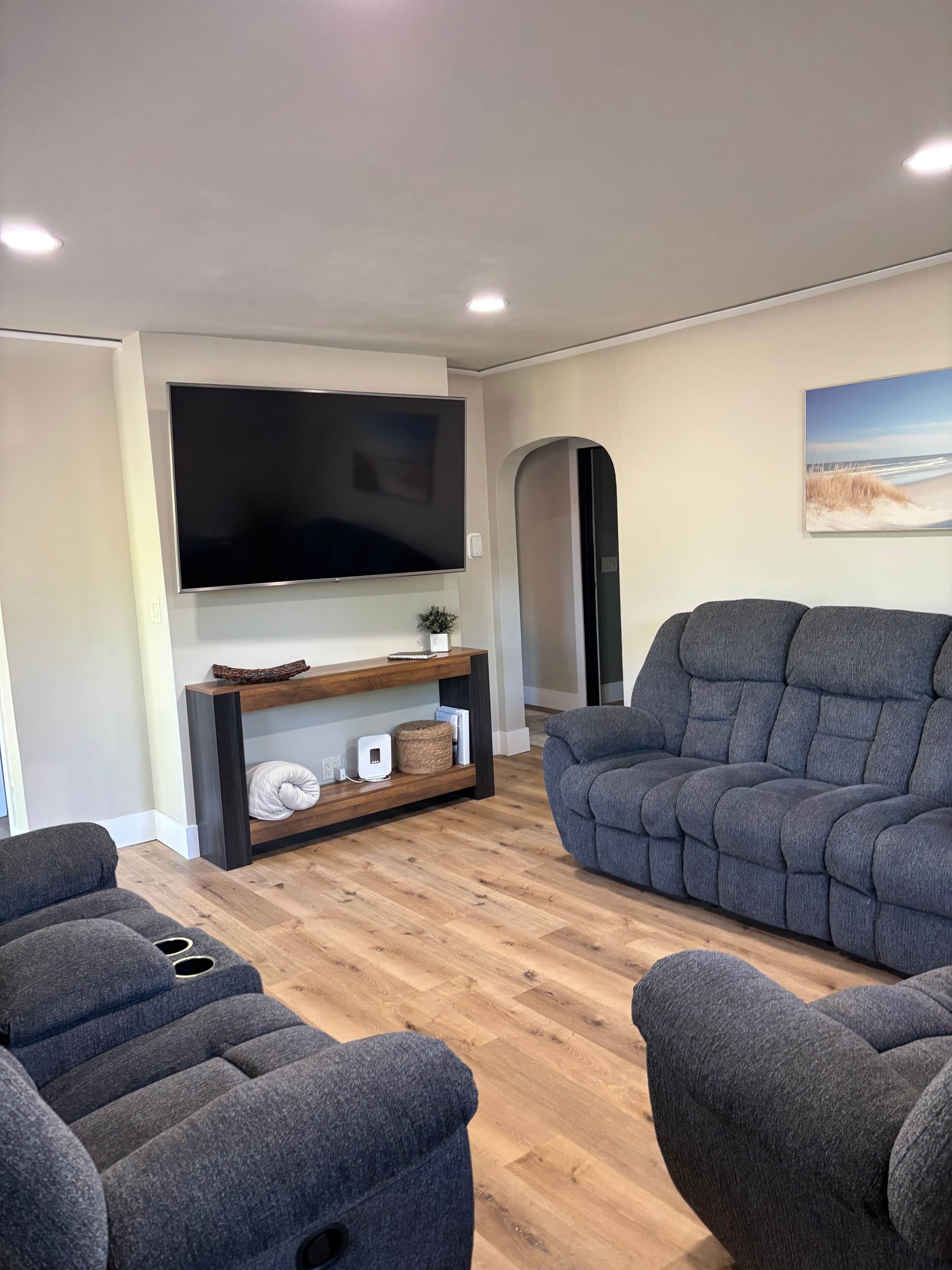 Un salon moderne doté d’un téléviseur à écran plat, d’un meuble de rangement en bois et de deux canapés gris.