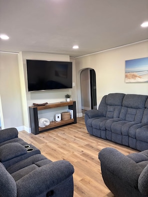 A modern living room with a flat-screen TV, a wooden entertainment unit, and two grey sofas. - The Maki House (Washburn)