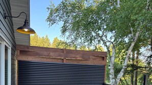 A wooden deck with a table and chairs, a metal railing, and a garage door.
