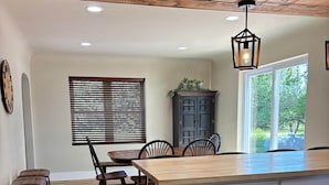 A kitchen with a wooden island, white cabinets, and a dining area with chairs and a table.
