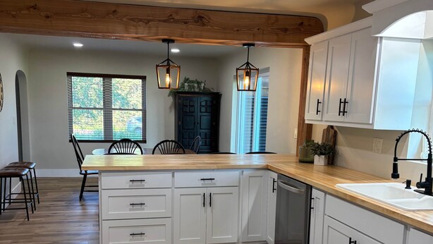 A kitchen with white cabinets, wooden countertops, and a central island.