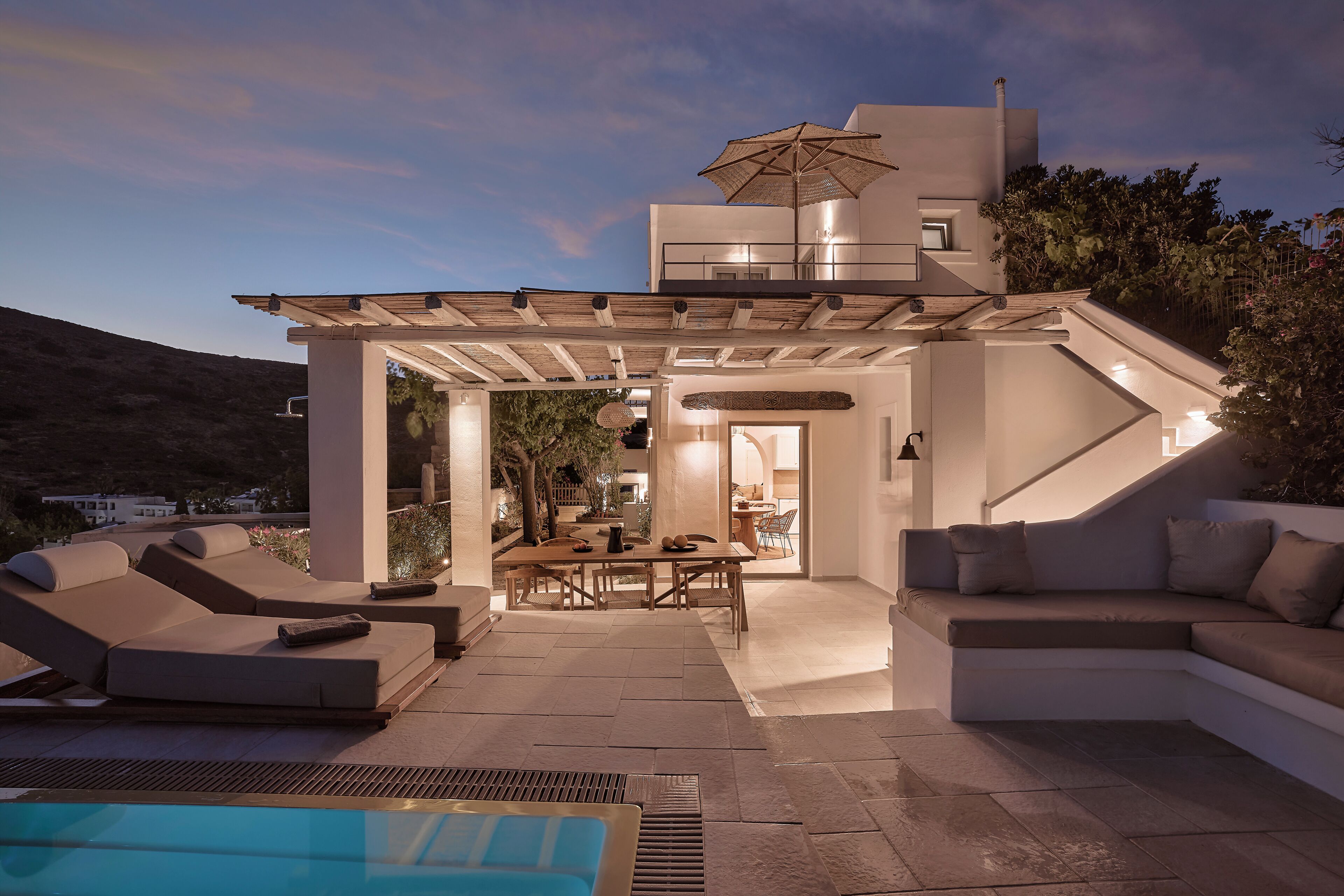 Un espacio exterior moderno con piscina, sillones de descanso y una mesa de comedor.