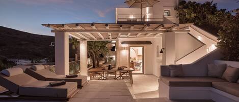 Un espacio exterior moderno con piscina, sillones de descanso y una mesa de comedor.