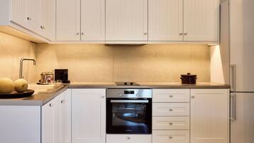 A modern kitchen with white cabinetry, a built-in oven, and a refrigerator.