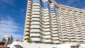 Un hotel de altura con piscina al frente.