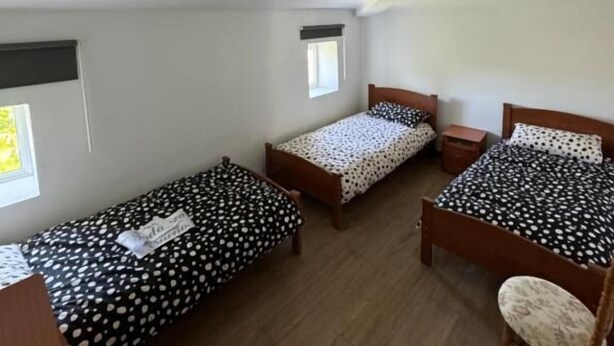 A room with two single beds, a wooden chair, a small table, and a window.