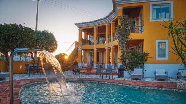 A swimming pool with a water feature, a building with balconies, a poolside, and outdoor furniture. - Studio Apartment With Pool Meia Praia Beach, Lagos (Lagos)