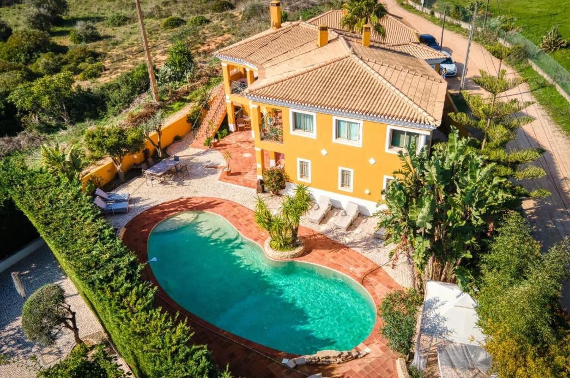 A large house with a swimming pool, surrounded by greenery.