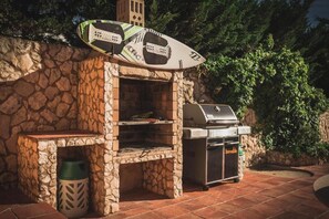 A stone-built outdoor kitchen with a grill and a surfboard. - Studio Apartment With Pool Meia Praia Beach, Lagos (Lagos)