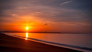 A sunset over a calm body of water with a beach in the foreground. - Studio Apartment With Pool Meia Praia Beach, Lagos (Lagos)