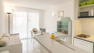 A modern kitchen with a dining area, a sofa, and a microwave.