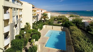 Un hotel con piscina, vista al mar y un edificio de varios pisos con balcones.