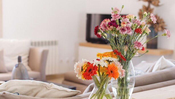 A living room with a sofa, a wooden coffee table, and a vase of flowers. - Luxury Villa on Prata Costa With Private Pool, Terrace With Lagoon View (Caldas da Rainha)
