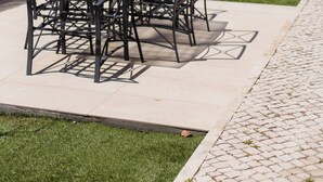 An outdoor patio with a glass table and metal chairs, surrounded by a low hedge and a paved walkway. - Luxury Villa on Prata Costa With Private Pool, Terrace With Lagoon View (Caldas da Rainha)