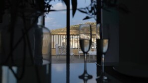 Un balcón con vistas a edificios y una mesa con copas de vino.