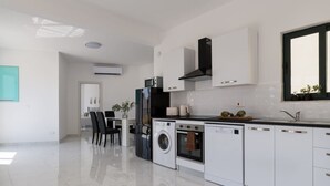 Una cocina moderna con una isla central, electrodomésticos integrados y un comedor con sillas.