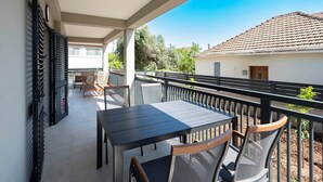 A balcony with a table and chairs, a metal railing, and a view of a building with a tiled roof. - #1 Holiday Apartment MTG - Orebić (Orebić)