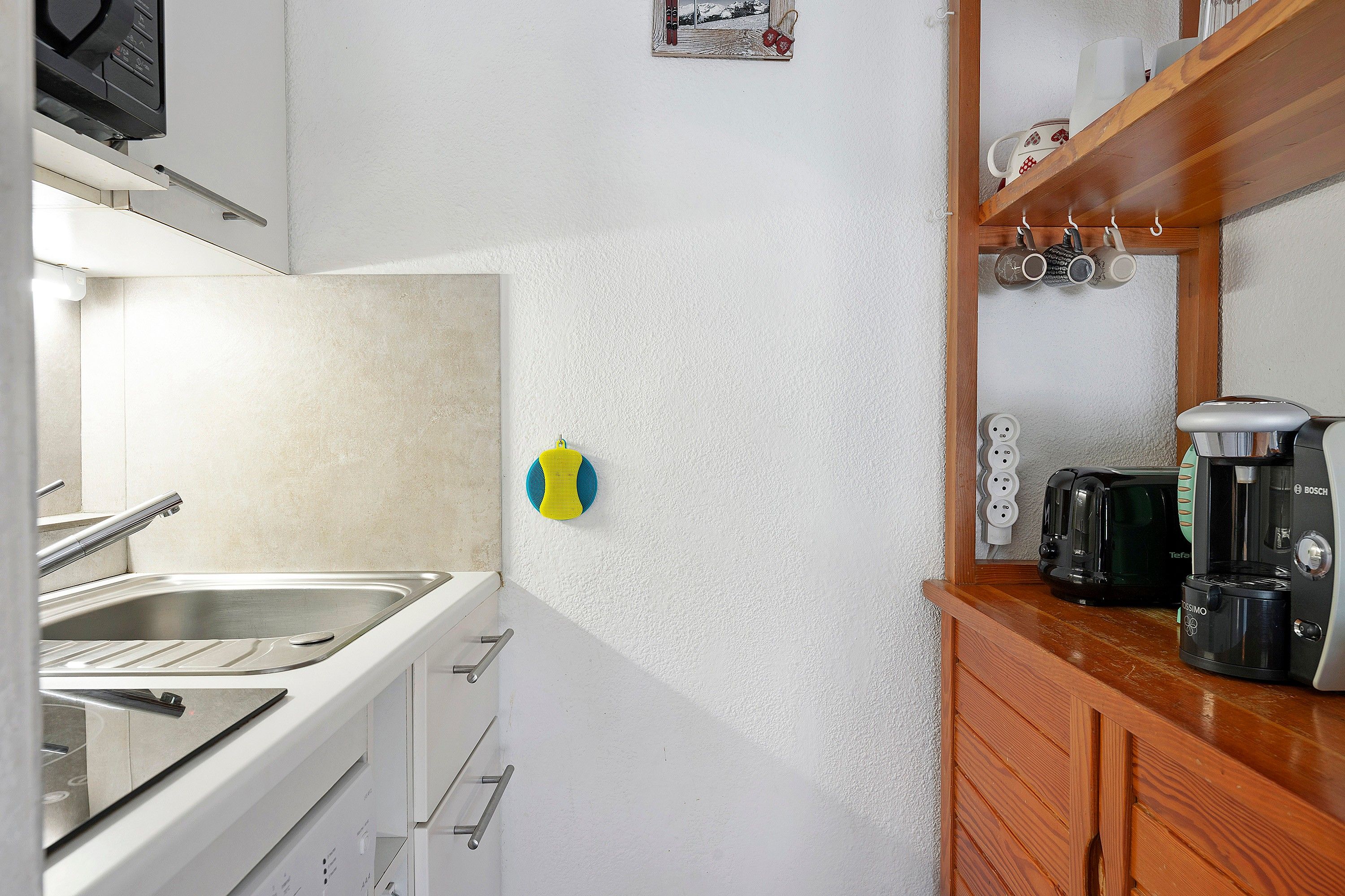 A kitchen with a sink, stove, and coffee maker.