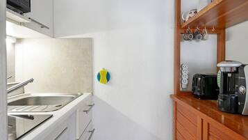 A kitchen with a sink, stove, and coffee maker.