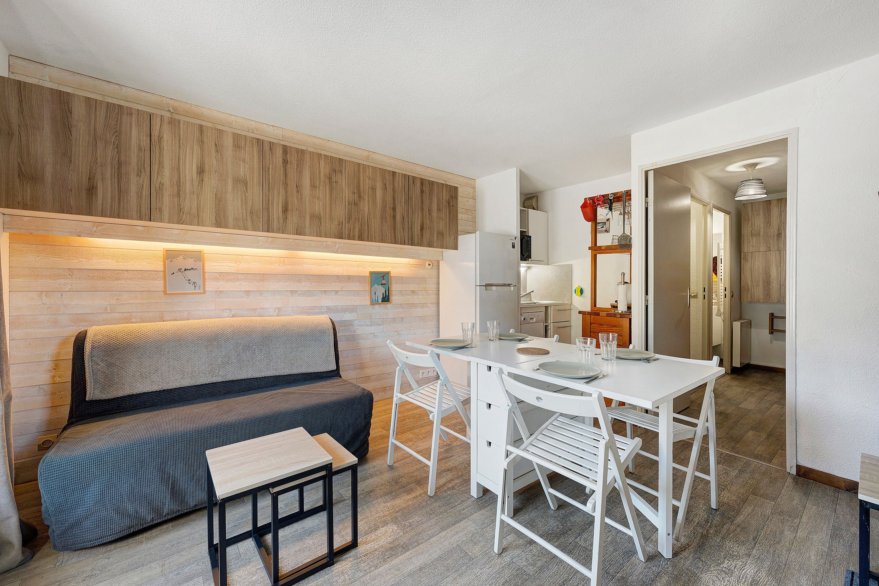 Un espace de vie compact comprenant un canapé, une table à manger et un coin cuisine.
