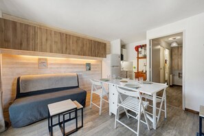 Un espacio habitable compacto con sofá, mesa de comedor y kitchenette.