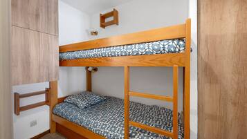 A bunk bed with a patterned mattress, a wooden headboard, and a small shelf above.