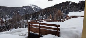 A wooden bench in a snowy outdoor area with a mountainous background. - Apartment 'Parenthèse Alpine' with Mountain View and Private Terrace (La Plagne-Tarentaise)